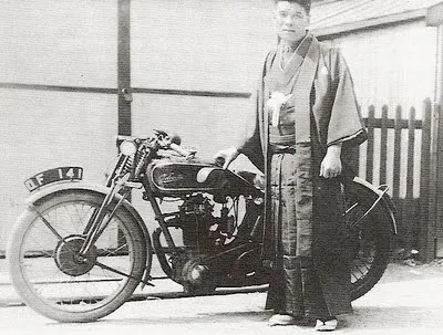 Vintage photograph of a rider in a kimono beside an early Japanese motorcycle